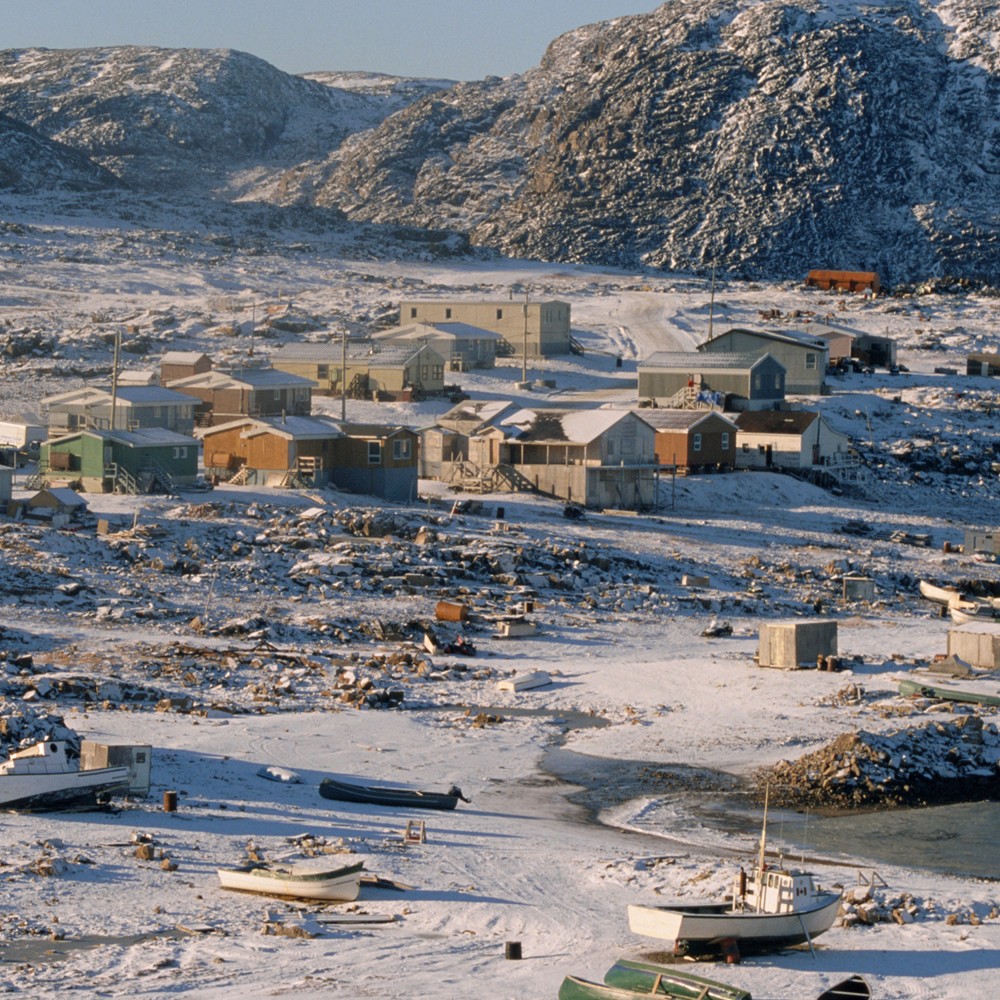 Aerial view of Arctic settlent showing scattered houses and boats set against a mountainous backdrop